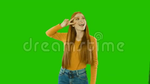 一个快乐的红发微笑的女孩一只手在她的脸附近显示一封信另一只手在她的腰带上拿着一个绿色的视频的预览图