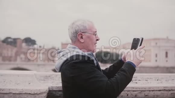 快乐兴奋的高级男性游客用智能手机慢动作拍摄意大利罗马古城建筑的照片视频的预览图