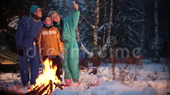 冬季森林一家人在火边的树林里拍照视频的预览图