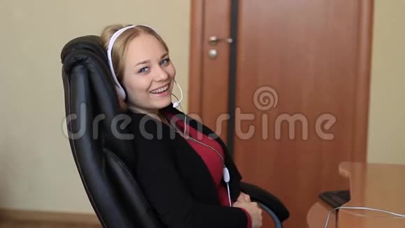 耳机里的女孩正坐在电脑附近的椅子上视频的预览图