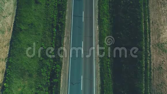 不同类型的汽车在穿过绿色草地和农业的空砾石路上行驶的空中模糊景象视频的预览图