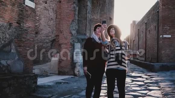 快乐的白种人母女在一起探索意大利庞贝的古老古董街道时拍了一张自拍照片视频的预览图