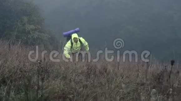 带背包的男徒步旅行者穿着信号背心是雾中的一座山视频的预览图