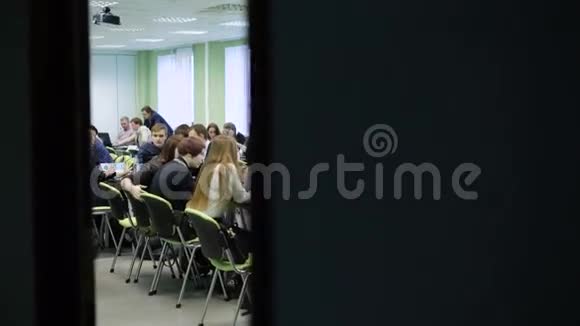 一大群人在一个光线充足的大教室里坐在桌子旁一起工作年轻的经济学家坐在那里视频的预览图