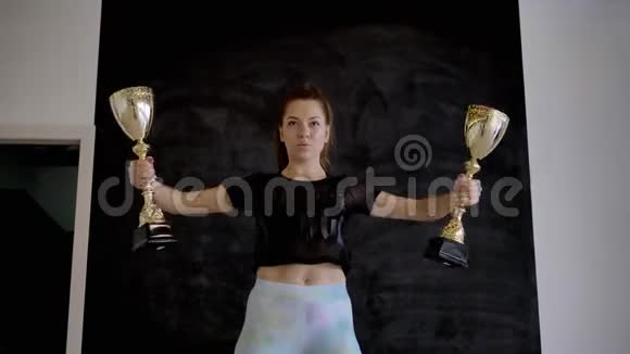 白人运动的黑发女子手中拿着金杯摆在镜头前视频的预览图