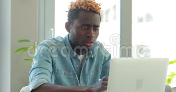 一位非洲裔美国商人写了一篇文章看着办公室里的笔记本电脑显示器视频的预览图
