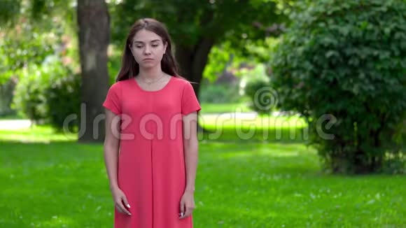 一个漂亮的年轻女人站在公园里突然她把手放在肚子上痛苦地扭动着视频的预览图
