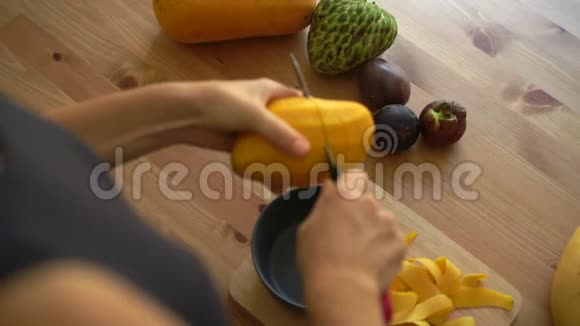 2倍慢镜头一位年轻女子将芒果切成方块桌上摆着许多热带水果视频的预览图