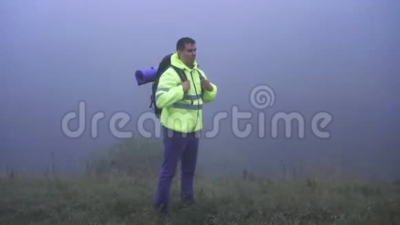 一个穿着信号背心的游客挺直背包戴上引擎盖走进雾中视频的预览图