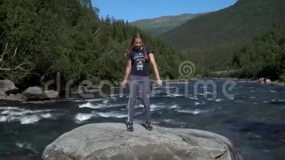一个女孩在山河的岩石上跳舞视频的预览图