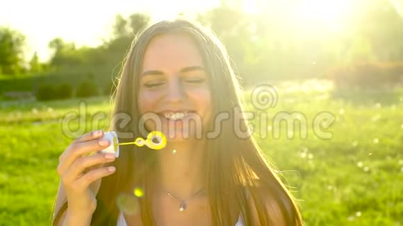 长发美女吹泡泡香皂在绿草公园自然户外快乐美女青少年视频的预览图