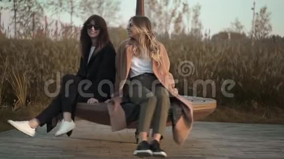 两个年轻的女人在公园的巨大的鞭子顶上打转做着滑稽的脸视频的预览图