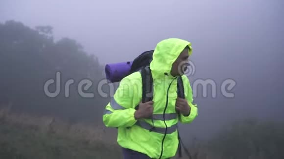 一名背着背包的男子游客的画像他独自在山中的雾中行走环顾四周视频的预览图
