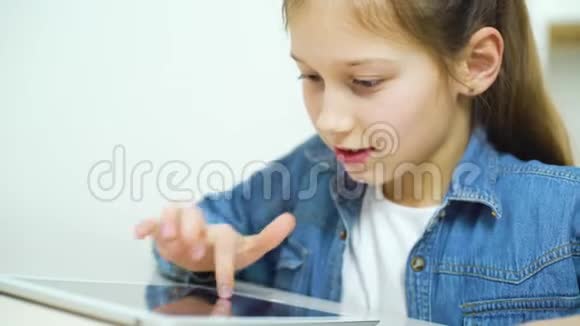 穿牛仔裤的小女孩穿着平板电脑玩游戏视频的预览图