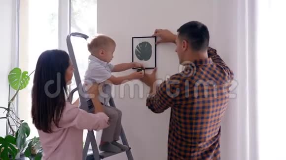 家庭修理可爱的孩子用测量带帮助父母修理和挂在公寓的照片视频的预览图