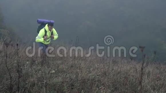 男子徒步旅行者背着背包在信号背心上山的雾中一慢莫视频的预览图