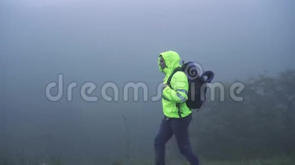 一位身穿信号背心头罩背包独自在雾中行走的游客关门视频的预览图