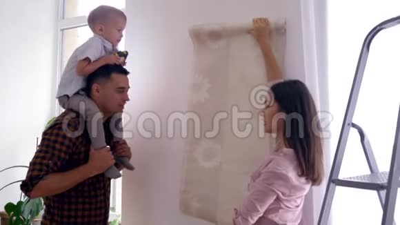 幸福的一家人在新家做修理幸福的爸爸妈妈和儿子肩上扛着肩选择了公寓的壁纸视频的预览图