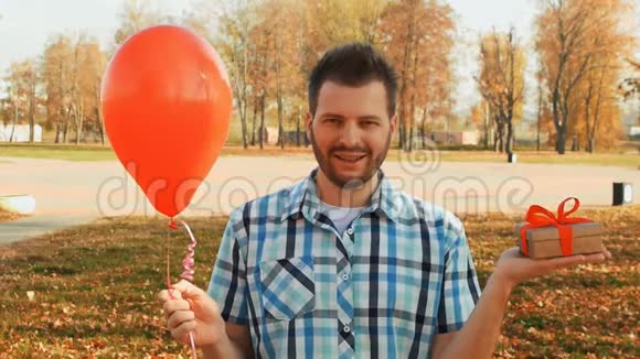 一个满脸胡须的男人手里拿着一个红色的气球和一个礼品盒视频的预览图