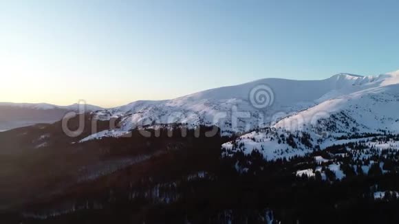 在白雪覆盖的山脉上的壮丽鸟瞰底部有许多树4k视频的预览图