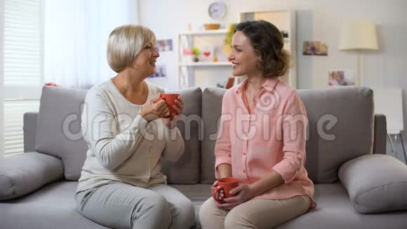 母女俩在家里聊天在沙发上喝杯咖啡放松信任视频的预览图