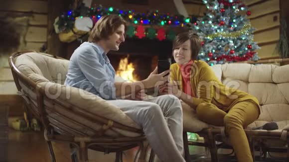 年轻人和女人使用智能手机男人和女人分享他的圣诞夜视频的预览图
