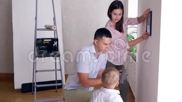 父亲在修理公寓时教小儿子用螺丝刀把架子栓到墙上视频的预览图