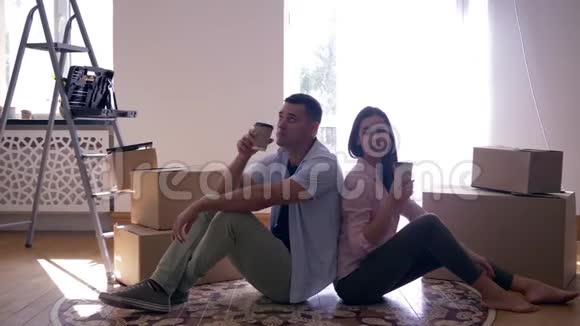 乔迁之喜年轻夫妇喜欢新公寓喜欢坐在地板上喝茶视频的预览图
