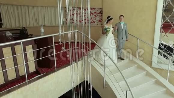 一对新婚夫妇幸福地走下酒店优雅的楼梯视频的预览图