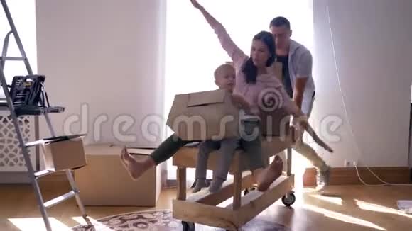 幸福的搬迁年轻人带着妻子和小儿子在新公寓的桌子上带着东西的盒子视频的预览图