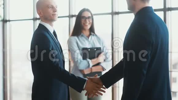 两位业务伙伴见面时握手动作缓慢背景中漂亮的女秘书视频的预览图