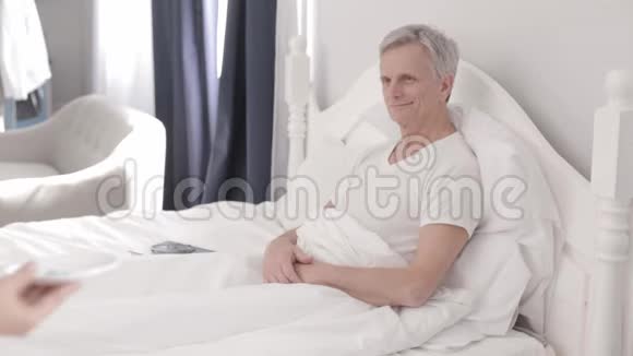 迷人的医生在床上照顾一位残疾老人视频的预览图