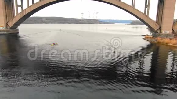 从桥下空中拍摄两个人漂浮在河上的独木舟上4K视频的预览图