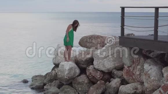 一个女人站在海边的岩石上视频的预览图