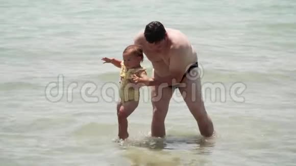 爸爸和小女孩穿着黄色的游泳衣在海里玩耍希腊雅典父亲视频的预览图