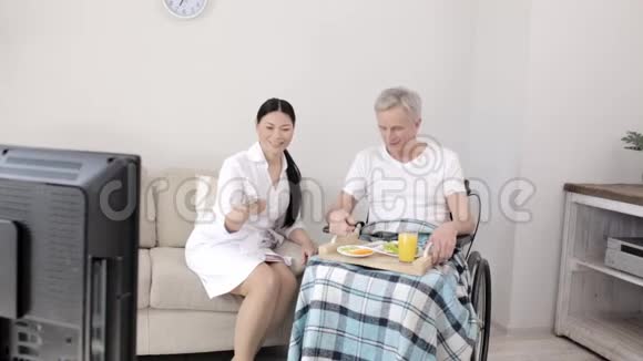 在当地的一家医院里一名护士在轮椅上照顾一名白发男子视频的预览图