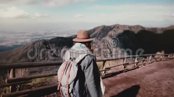 从维苏威火山出发带着相机徒步旅行的年轻开朗的旅游女孩转过身来微笑着视频的预览图