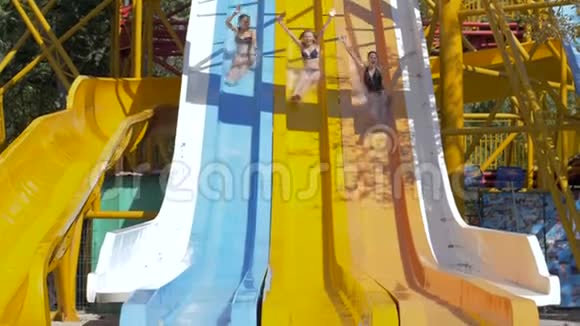 水上公园年轻女子在水上滑滑梯上翻滚进入游泳池在假日尽情狂欢视频的预览图