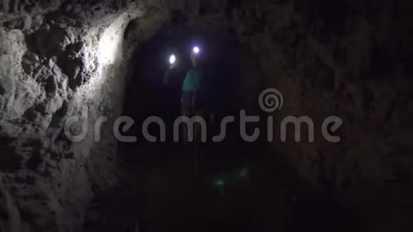 女孩游客背着一个背包额头上拿着手电筒手里拿着一个黑暗的洞穴正在探索它视频的预览图