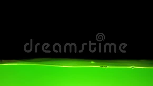 明亮的绿色水在黑色的背景上摇动视频的预览图
