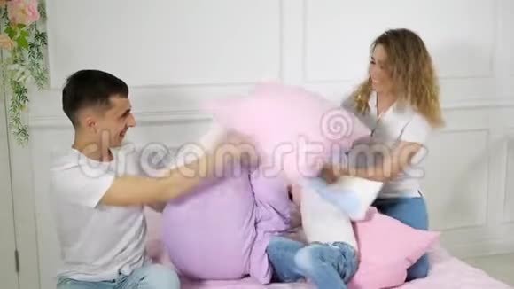 小家庭爸爸妈妈和小儿子在床上玩枕头大战视频的预览图