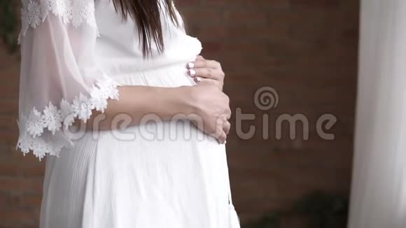 特写镜头一个长发黑发怀孕模特摆在白色的黑人美丽的白种人女人爱抚她视频的预览图