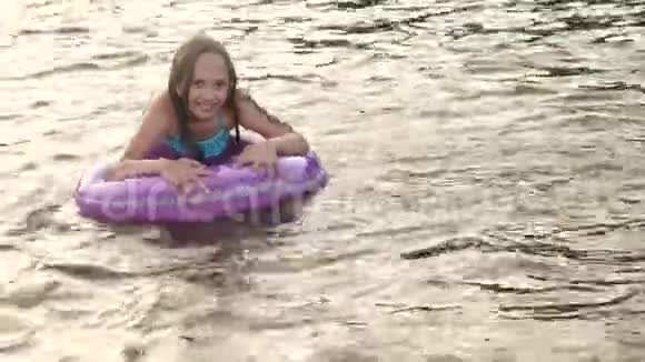 小女孩在水中游泳在一个充气的圆圈里女孩笑着潜水视频的预览图
