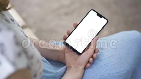 女性手拿白色屏幕的智能手机使用智能手机将智能手机与绿色屏幕放在时尚上视频的预览图