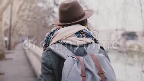 在冬季的罗马慢动作中带背包沿着泰伯河在飞机树下散步的女性游客的后景视频的预览图