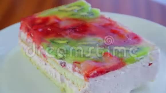 水果蛋糕上有猕猴桃和草莓果冻放在白色盘子里旋转成一圈视频的预览图