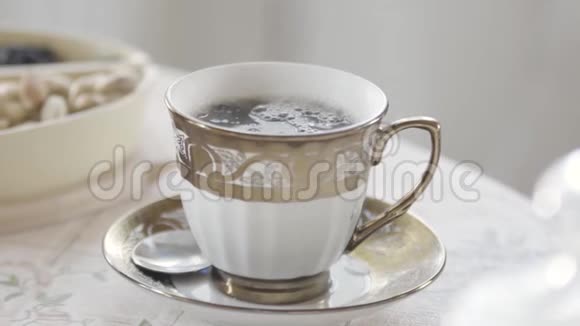 在光线充足的房间里用蒸汽把优雅的瓷杯热茶放在桌子上库存录像贵族视频的预览图