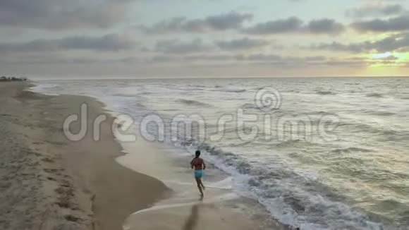 清晨女人独自在海岸上奔跑日出视频的预览图