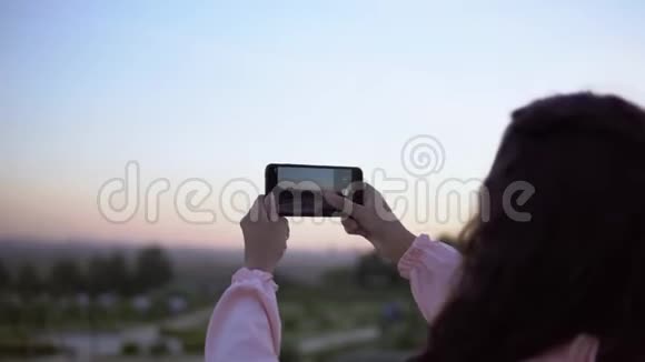一个女孩正在智能手机上拍摄这座城市的照片4K视频的预览图