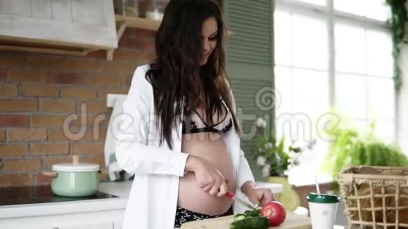 特写镜头一个怀孕的白种人长着深色头发在家厨房里切蔬菜目标镜头视频的预览图